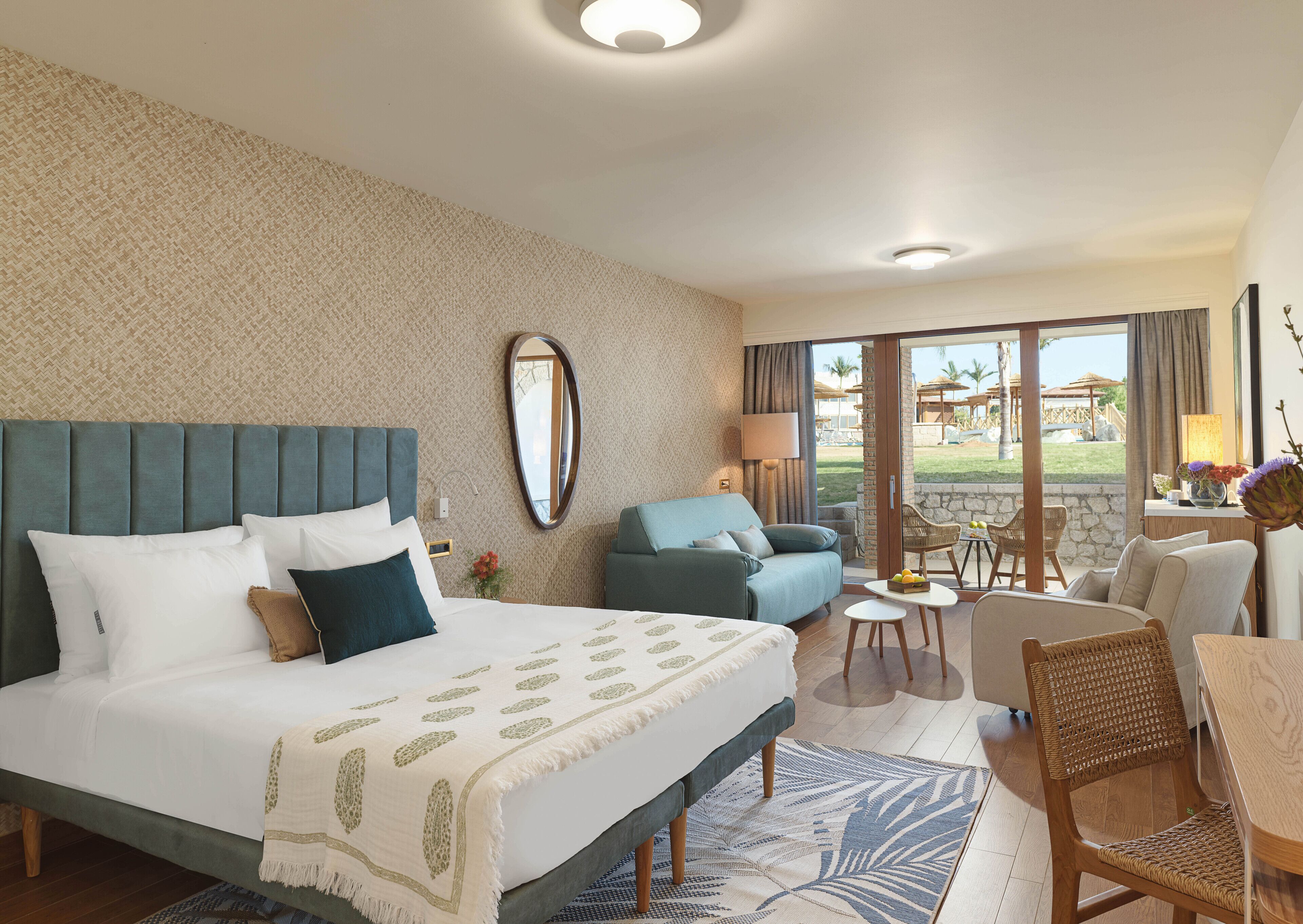 Une chambre d’hôtel dotée d’un grand lit, d’un canapé, d’un coin repas et offrant une vue sur l’extérieur.
