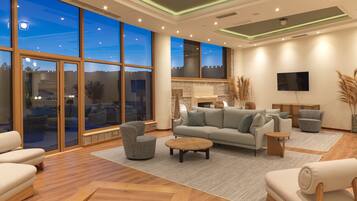 A spacious living room with a large window, a sofa set, and a flat-screen TV.