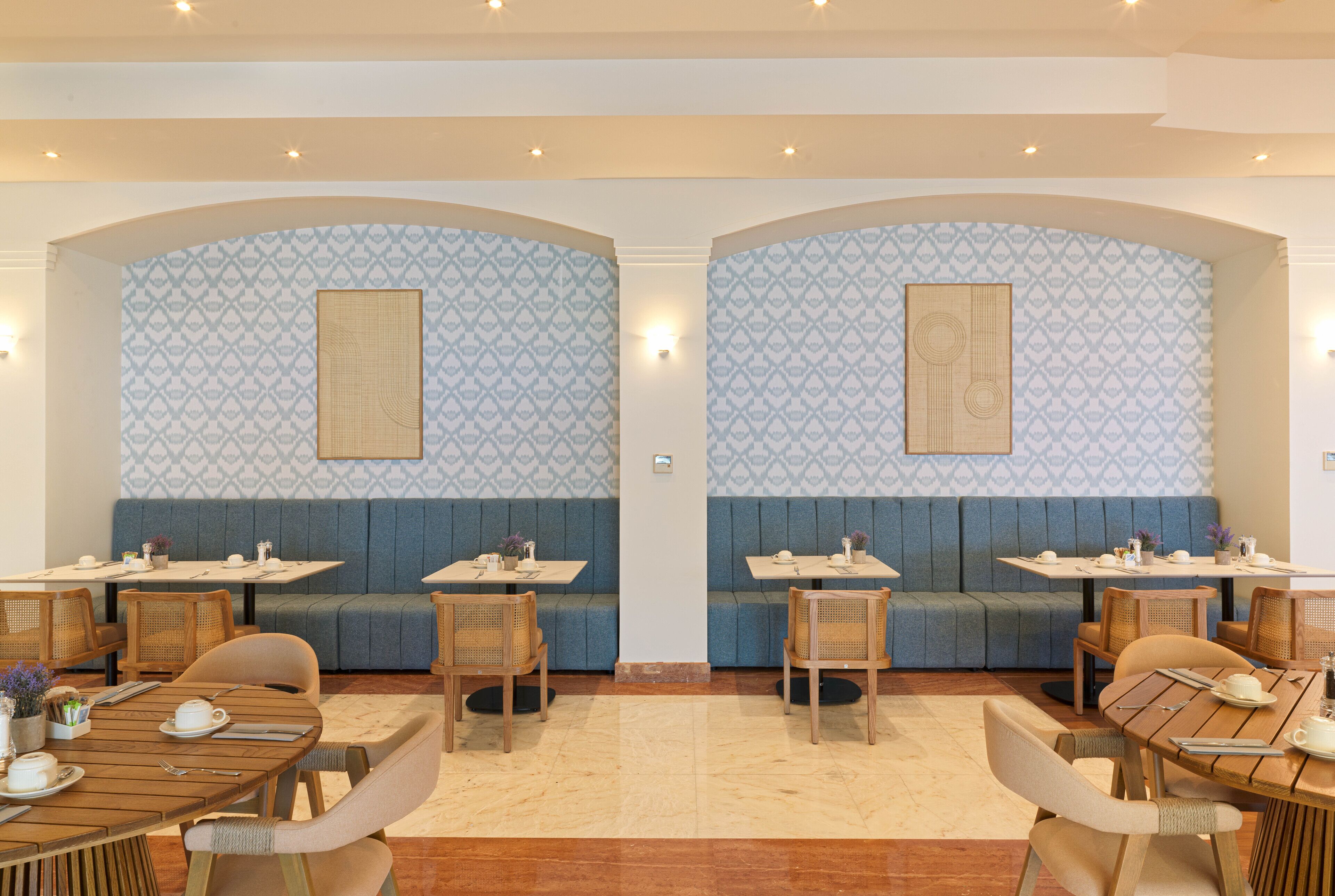 Ein Restaurant mit Sitzgelegenheiten in Form von Boxen und Tischen, mit gestreifter Tapete und Holzmöbeln.