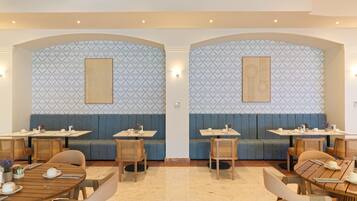 Ein Restaurant mit Sitzgelegenheiten in Form von Boxen und Tischen, mit gestreifter Tapete und Holzmöbeln.