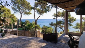 Un ponte di legno con vista sul mare, arredi da esterno e un pergolato.