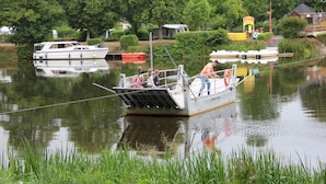 Una pequeña embarcación amarrada en un río tranquilo con algunas personas a bordo.