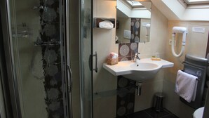 Un baño con cabina de ducha de vidrio, lavamanos, espejo e inodoro.