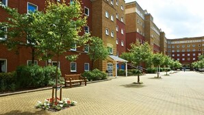 A courtyard with a brick building, a bench, and a covered seating area. - Great Dover Street Apartments, King’s College London (London)
