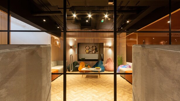 A modern interior with a herringbone wood floor, a central seating area with a table, and a view through a glass partition. - Great Dover Street Apartments, King’s College London (London)