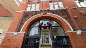 A brick building with a large arched entrance, a "NO PARKING" sign, and a staircase leading to the entrance. - Great Dover Street Apartments, King’s College London (London)