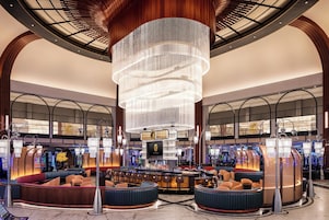 A spacious lobby with a central bar area, multiple seating options, and a large, illuminated chandelier.