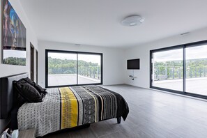 Relax in a stylish room with a large bed, flat-screen TV, and a view of the lush green landscape.
