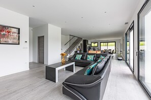 Relax in style with a spacious living area featuring a comfortable sofa, staircase, and large window offering a view of the outdoors.