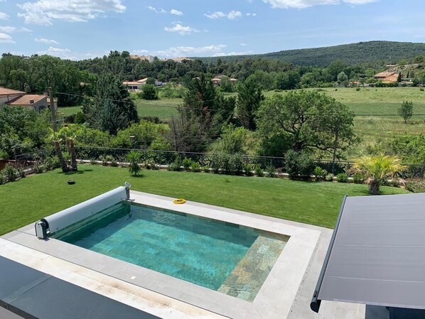 Enjoy a refreshing swim in the pool surrounded by a well-maintained lawn and lush green surroundings.