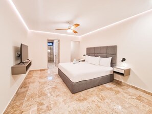 Relax in a spacious room with a large bed, flat-screen TV, and ceiling fan.