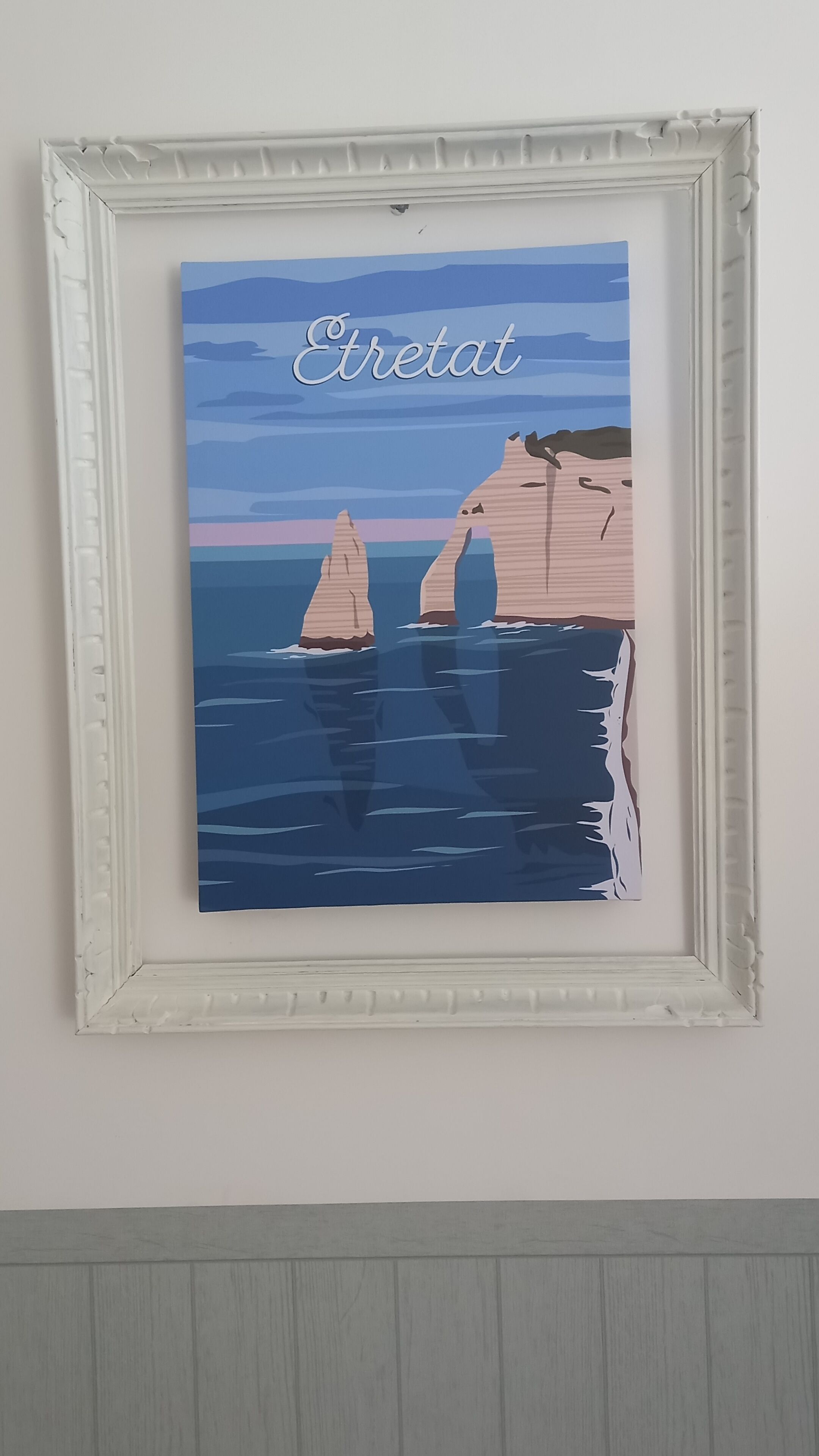 A framed artwork depicting two sailboats on a calm sea with a sunset in the background.