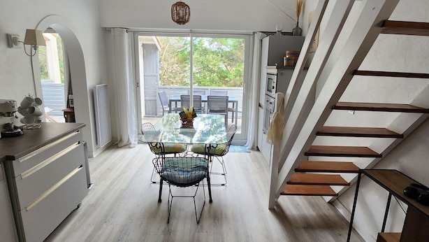 Een keuken met een eettafel en stoelen, een trap en uitzicht op de omgeving.