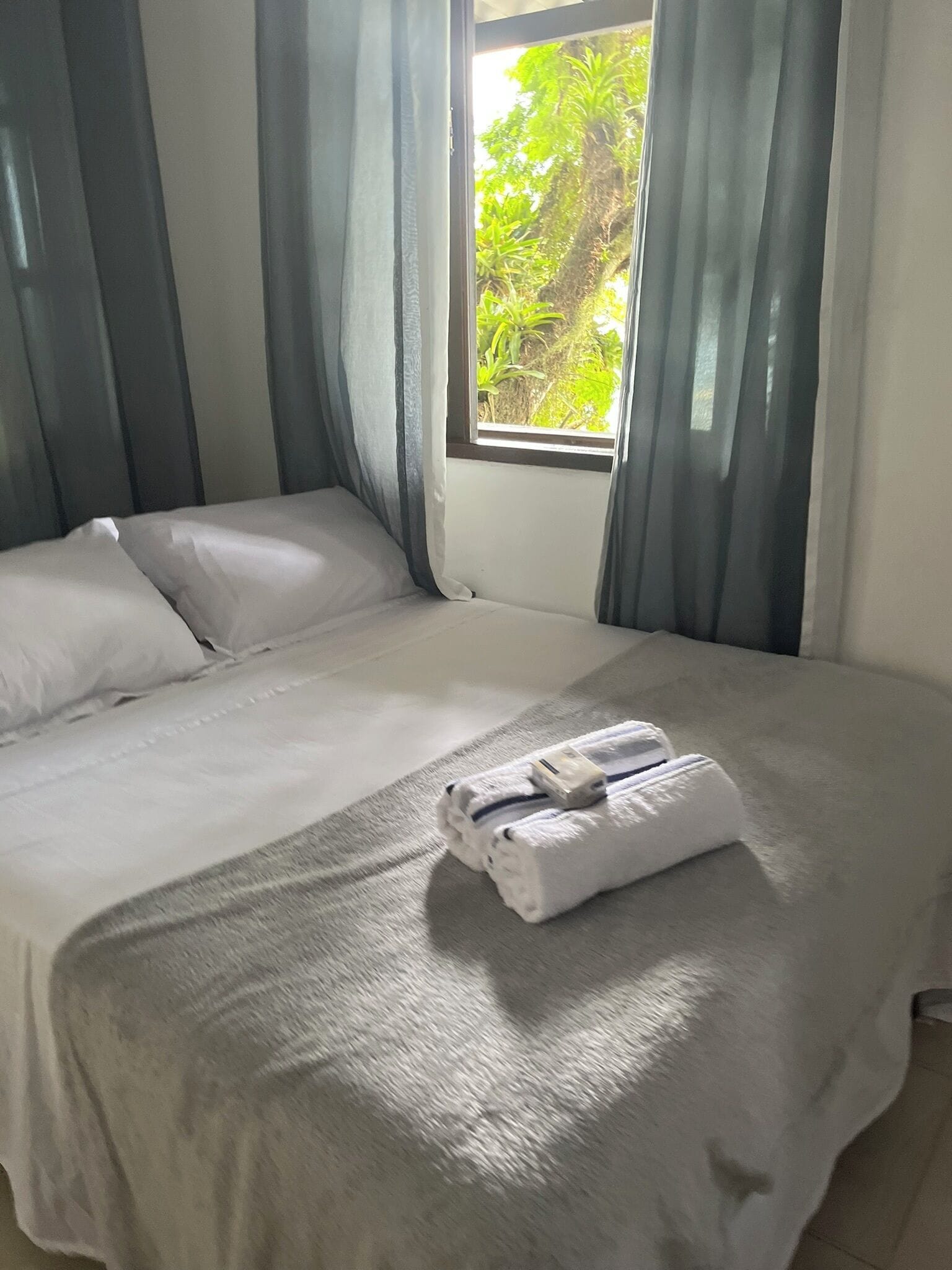 A neatly made bed with white linens and a folded towel on the bed.