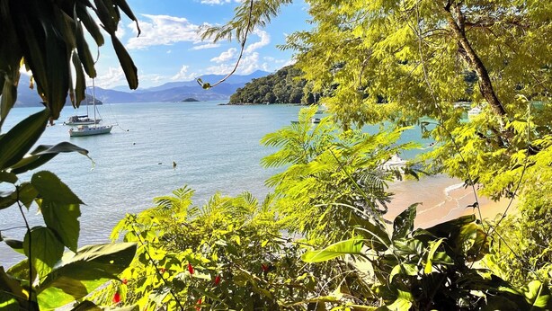 A tropical beach with boats, lush greenery, and a clear view of the sea. - Praia Comprida Flats (Angra dos Reis)