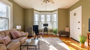 A living room with a sofa, coffee table, and a large window. - Stylish comfortable period feature 2 bed - Sun drenched - Free parking (Providence)