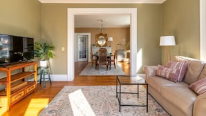 A living room with a TV, sofa, coffee table, and a dining area with a table and chairs. - Stylish comfortable period feature 2 bed - Sun drenched - Free parking (Providence)