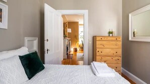 A bedroom with a bed, a dresser, and a door leading to a hallway. - Stylish comfortable period feature 2 bed - Sun drenched - Free parking (Providence)
