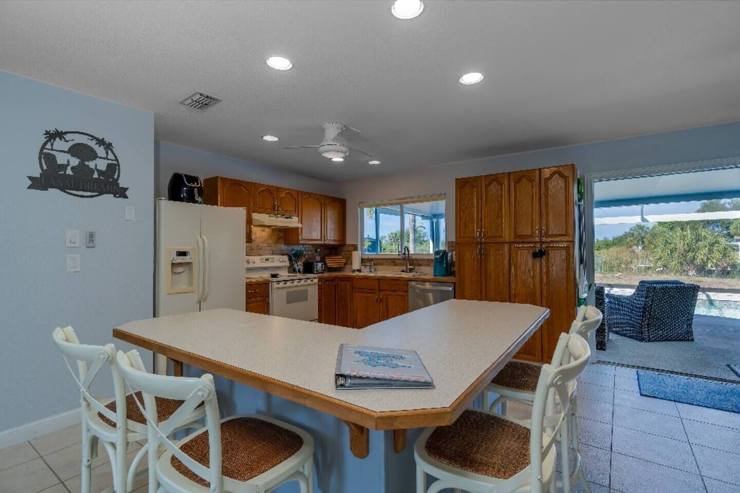 A kitchen with wooden cabinets, a white refrigerator, and a dining table with four chairs.