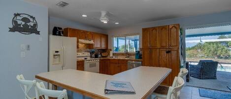 A kitchen with wooden cabinets, a white refrigerator, and a dining table with four chairs.