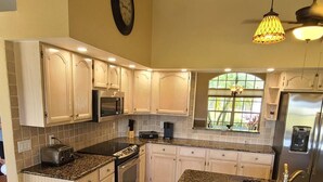 Una cocina amplia con una isla grande, encimeras de granito y electrodomésticos de acero inoxidable.