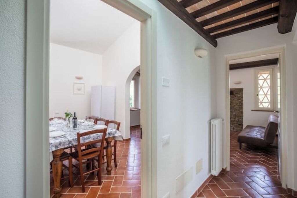 A dining area with a table set for four, a stone fireplace, and a view of a stone wall.