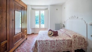 Un dormitorio con cama, armario de madera y vista a través de una puerta.