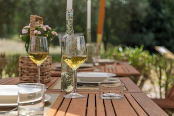 A wooden table set for a meal with wine glasses and a bottle.