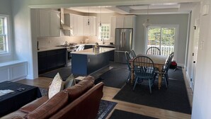 Una cocina moderna con armarios blancos, una isla central y un comedor con mesa y sillas.