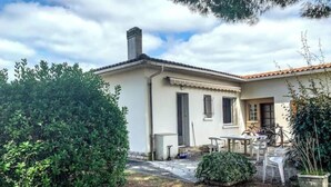 A single-story house with a tiled roof, a chimney, and a small patio with a table and chairs. - La marmotte - Holiday home - Les Mathes (Les Mathes)