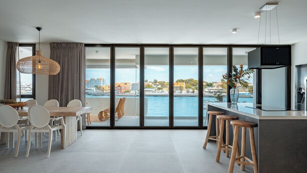 A modern kitchen with a large island, bar stools, and a dining area with chairs and a table.