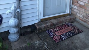 A white door with a wreath, a mailbox, and a doormat with "WELCOME" written on it.
