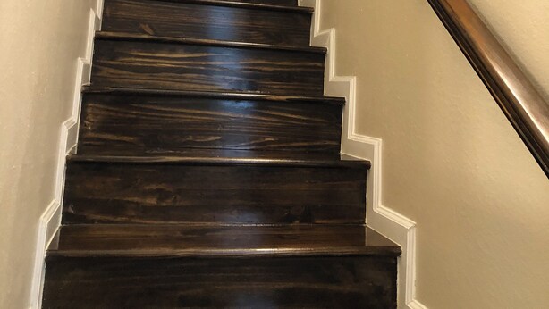A wooden staircase with white trim and a handrail.