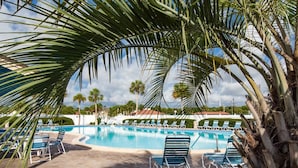 A pool area with lounge chairs and palm trees. - Ocean and Racquet #5217 (St. Augustine)