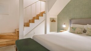 A modern bedroom with a wooden staircase, a bed with a green headboard, and a bedside lamp. - Sbucks - Trendy Space in Porto - Next to Ribeira (Porto)