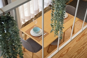 A dining area with a wooden table, grey chairs, and a hanging plant. - Sbucks - Trendy Space in Porto - Next to Ribeira (Porto)