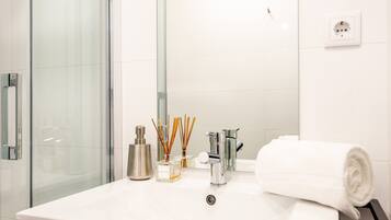 A bathroom with a white sink, a mirror, a towel, and a glass shower enclosure.