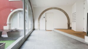 A hallway with a glass wall on one side and a door at the end. - Foz003 · Light-filled Studio With Courtyard Garden (Porto)