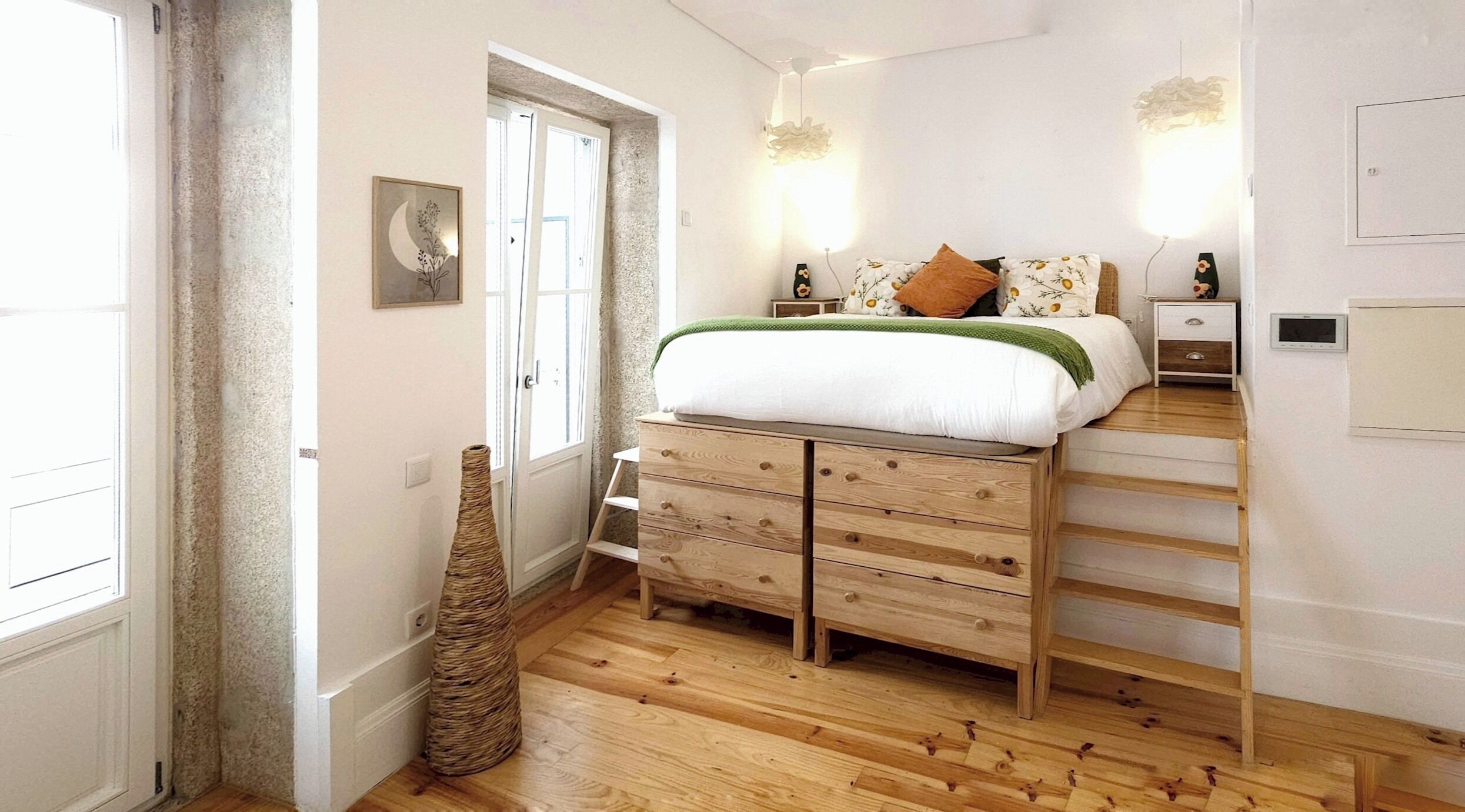 Un dormitorio con cama, cómoda de madera, mesitas de noche y una cesta tejida.
