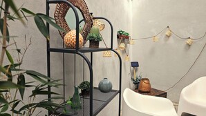 A metal shelf with decorative items, a white chair, and a small table with a solar-powered device.