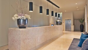 A modern reception area with a marble counter, black pendant lights, and a large potted plant. - Gary01 Exclusive Top Floor 2BD by the Timeout Market (Lisbon)