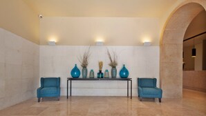 A lobby with a marble floor, a reception desk, two blue armchairs, and a wall-mounted light fixture. - Gary01 Exclusive Top Floor 2BD by the Timeout Market (Lisbon)