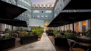 An outdoor dining area with tables and chairs, surrounded by planters and umbrellas. - Gary01 Exclusive Top Floor 2BD by the Timeout Market (Lisbon)