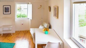 A room with a white table, a white bench, a green rug, and a window with a view of greenery. - Flora3 Flora Apartments, Studio w/ Garden View (Porto)