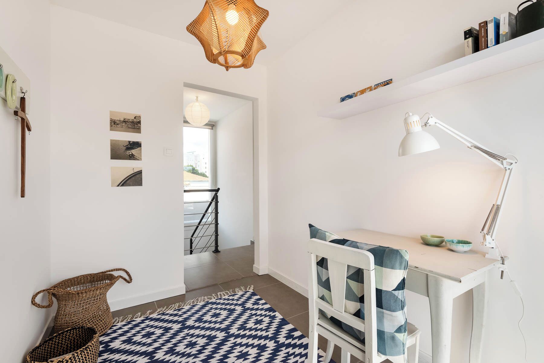 Una habitación moderna y bien iluminada, con escritorio, silla y lámpara colgante.