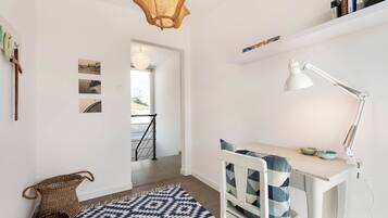 Una habitación moderna y bien iluminada, con escritorio, silla y lámpara colgante.