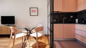 A modern kitchen with peach cabinets, a glass dining table, and a flat-screen TV. - Rivol2 · Wonderful 1BR Next to Rivoli Theatre (Porto)