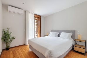 A bedroom with a large bed, a potted plant, a nightstand, a lamp, and a window with curtains. - Rivol3 · Stunning 1BR w/ Private Terrace (Porto)