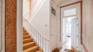 Una scala con gradini in legno e ringhiere bianche conduce a una stanza con la scritta 'AL'.