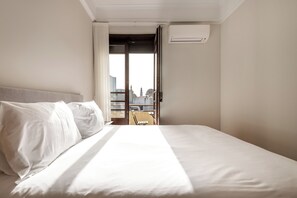A hotel room with a bed, a view of the cityscape through an open door, and an air conditioning unit on the wall. - Rivol5 · Unique Flat Very Central @rivoli (Porto)